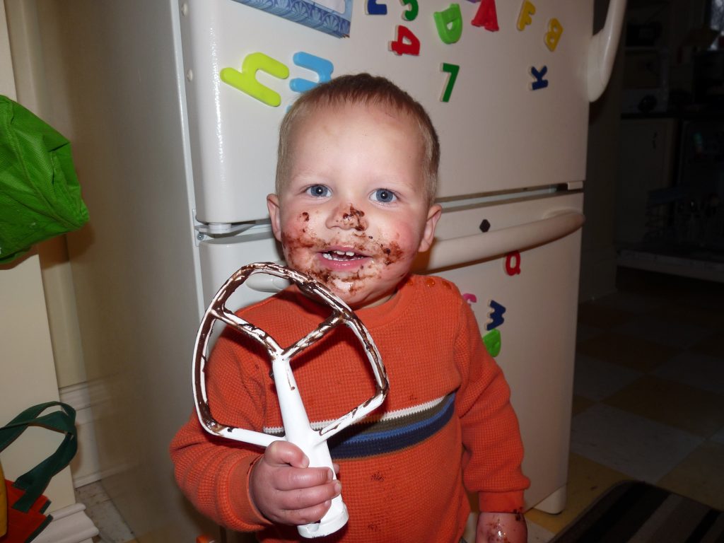 What can happen in twenty years? Forgotten Memories: Toddler eating chocolate batter off a mixer attachment in front of a refrigerator. Boy has chocolate all over his face and a big smile.